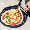 Pizza peel with wooden handle removing margherita pizza from black cast iron skillet