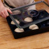 Black cast iron dough tray with six round wells on wooden surface