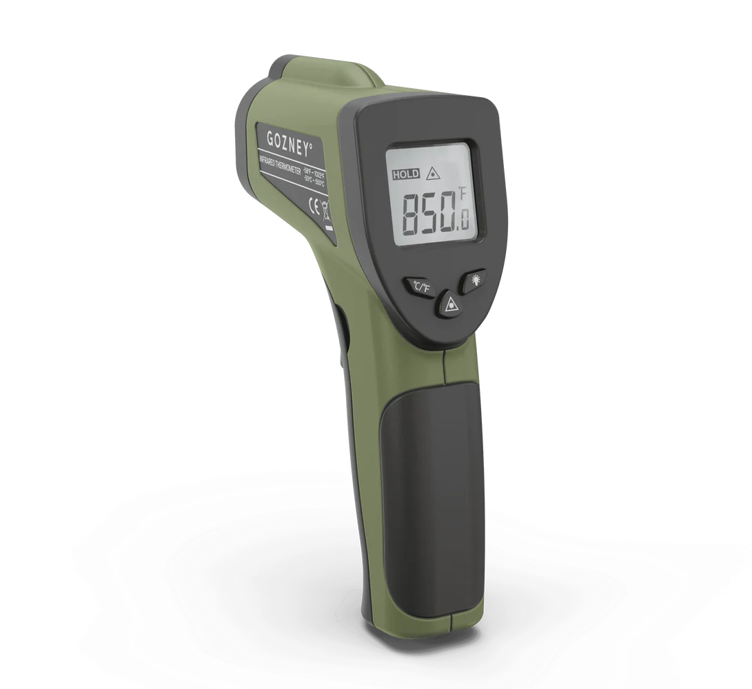Gozney infrared thermometer gun with olive green body, black handle, and digital display showing temperature reading