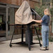 Gozney pizza oven protective cover in beige fabric on outdoor wood-fired oven with stand