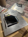 Built-in grill box with stainless steel lid, black interior grate, and control handle on display table