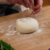 Fresh mozzarella ball on wooden surface with flour dusting