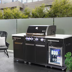 Black modular outdoor kitchen island with gas grill, cooktop, mini fridge, and storage cabinets on patio